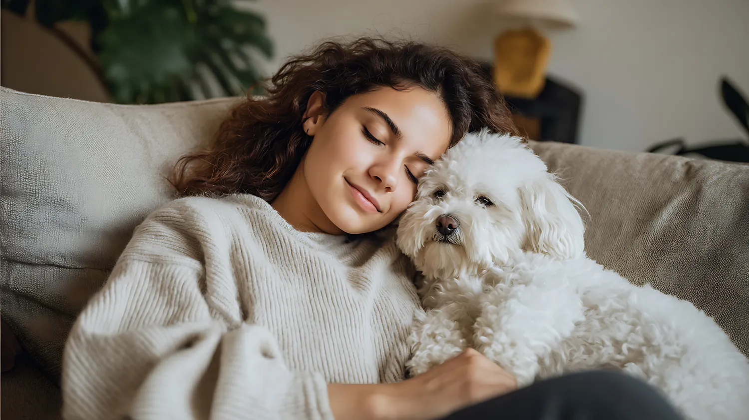 HanseMerkur Versicherung - Tierversicherung - Eine Frau schläft friedlich auf dem Sofa, ein weißer Hund ruht neben ihrem Gesicht.