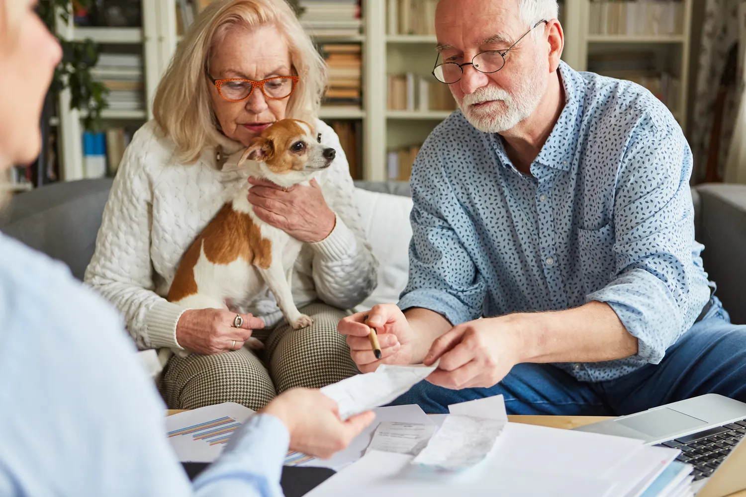 HanseMerkur Versicherung - Tierversicherung - ein Seniorenpaar und ein kleiner Hund schauen sich Finanzunterlagen an